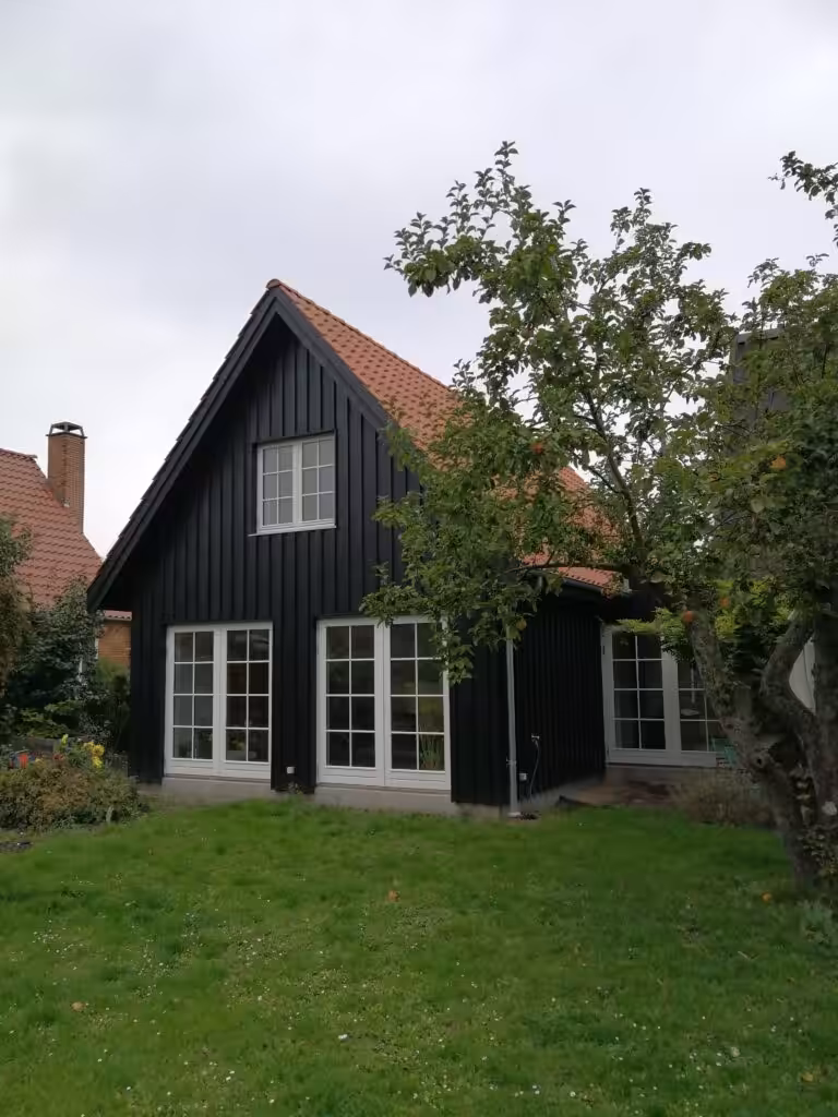 Tilbygning i sort træ med tilhørende have